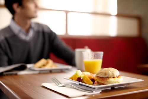 a man sitting at a table with a plate of food and orange juice at Hyatt Place Canton in Lake Cable
