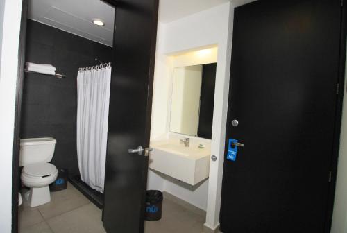 uma casa de banho com um WC branco e um lavatório. em Nu Hotel em Veracruz