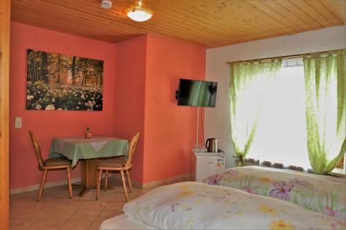 a bedroom with orange walls and a table and a bed at Gästehaus Willaringen in Rickenbach