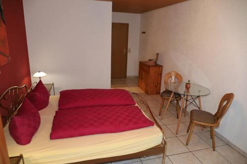 a bedroom with a bed with red sheets and a table at Gästehaus Willaringen in Rickenbach