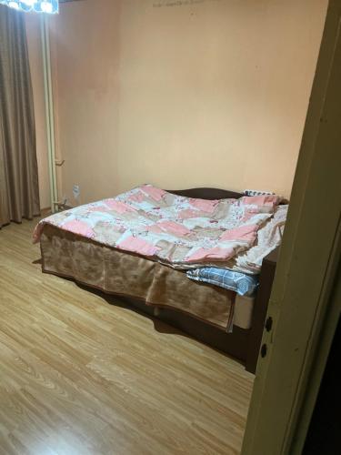 an unmade bed in a room with a wooden floor at Апартамент in Varna City