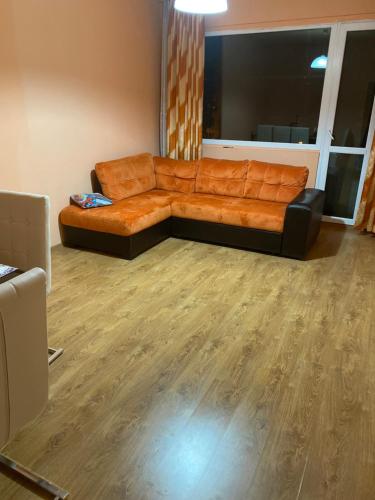 an orange couch in a living room with a wooden floor at Апартамент in Varna City