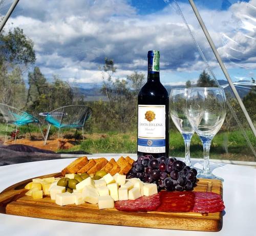 een fles wijn en een bord kaas en druiven bij Sky Glamping Colombia in Fúquene