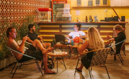 a group of people sitting around a table in a restaurant at Distrito Hostel in Santa Marta