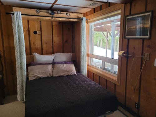 - un petit lit dans une chambre avec fenêtre dans l'établissement Whispering Pines Suite at The Bowering Lodge, à Blue Mountains