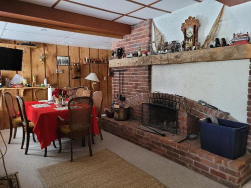 sala de estar con chimenea de ladrillo, mesa y sillas en Whispering Pines Suite at The Bowering Lodge, en Blue Mountains