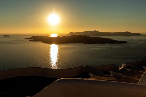 a sunset over a small island in the water at Villa Thiranthemis in Fira