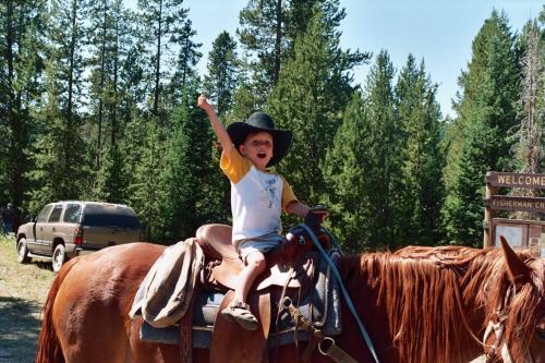 a young boy riding on the back of a horse at Spring Creek Ranch in Jackson