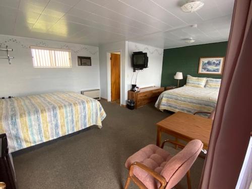 a hotel room with two beds and a desk and a television at Lamplighter Lodge in Panguitch