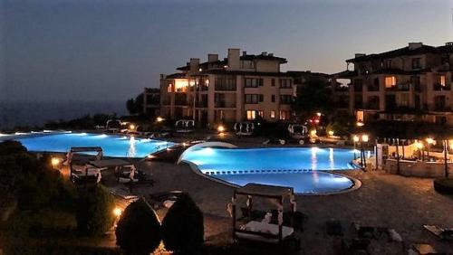 a large swimming pool at night with buildings in the background at Kaliakria Infinity Pool Apartment in Topola