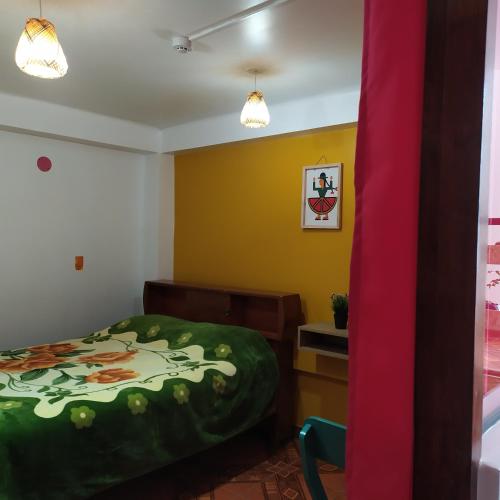a bedroom with a bed with a green comforter at The Chusay Rooftop in Cusco