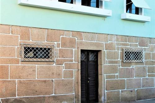 a brick building with a black door and two windows at BABhouse Casa da Mata - Coração do Douro in Nagoselo do Douro