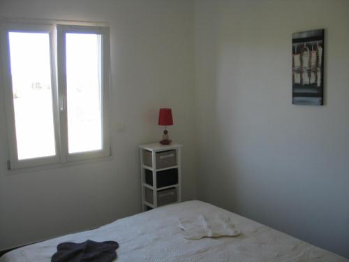 a bedroom with a bed and a lamp and a window at Les Romarins in Aigne
