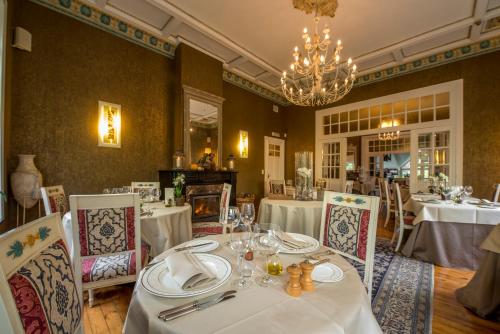 una sala da pranzo con tavoli, sedie e lampadario a braccio di Hotel La Ferronniere a Bouillon