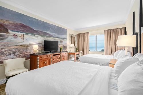 Habitación de hotel con 2 camas y TV de pantalla plana. en The Inn at Long Beach, en Long Beach