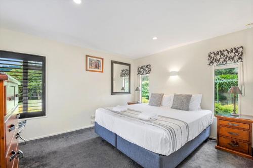 a bedroom with a large bed and two windows at Acacia Waters - Lake Taupo in Taupo