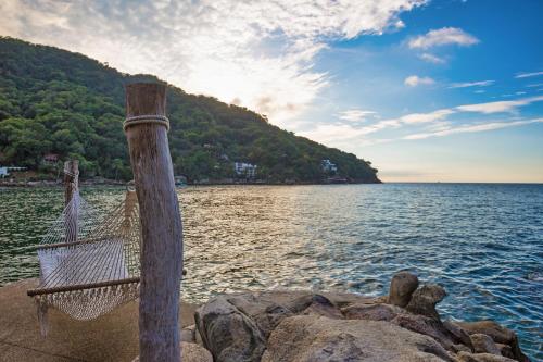 a hammock on a pole next to a body of water at Villa Lala Boutique Hotel Adults Only in Puerto Vallarta