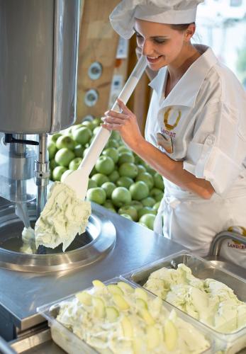 a woman in a kitchen preparing food on a machine at Landzeit Tauernalm in Flachau