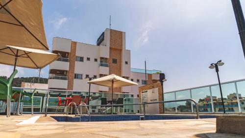 a pool with tables and umbrellas in front of a building at UPG Hotel in Ubatuba