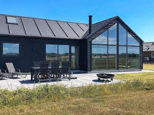 ein schwarzes Haus mit einem Tisch, Stühlen und Fenstern in der Unterkunft 10 person holiday home in Odder in Odder