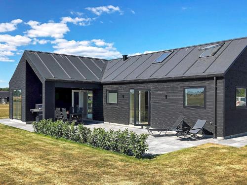 ein schwarzes Haus mit zwei Stühlen im Hof in der Unterkunft 10 person holiday home in Odder in Odder
