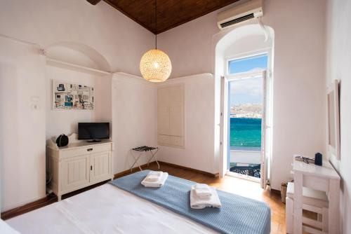 a room with a bed and a television and a window at Mykonos Old Harbor Front Suite with Balcony in Mikonos