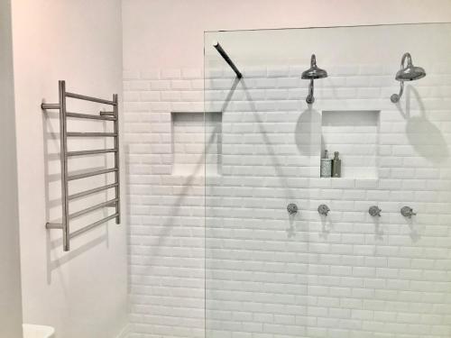 y baño con ducha y pared de ladrillo blanco. en Arcadia House, en Byron Bay