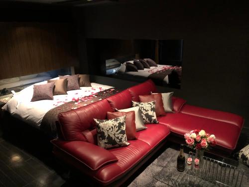 a red leather couch in a room with two beds at Hotel Patio in Hiroshima