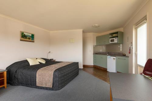 a bedroom with a large bed and a kitchen at The Bay Motel in Half-moon Bay
