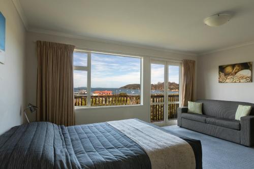 a bedroom with a bed and a couch and a large window at The Bay Motel in Half-moon Bay