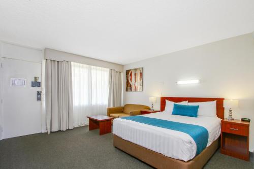 a hotel room with a large bed and a chair at Thunderbird Motel Yass in Yass