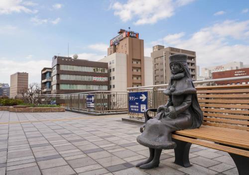 eine Statue einer Person, die auf einer Bank sitzt in der Unterkunft APA Hotel Kokuraeki Shinkansenguchi in Kitakyūshū