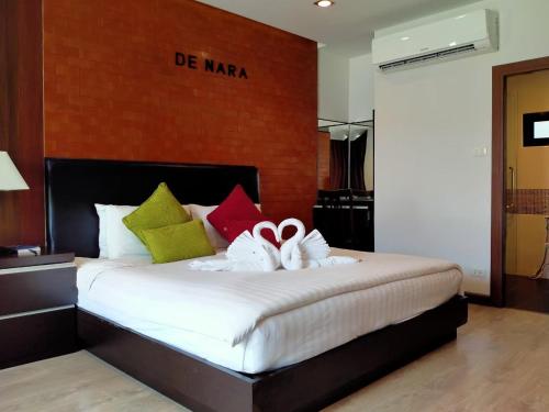 チェンマイにあるHotel De Naraのベッドルーム(大きな白いベッド、カラフルな枕付)