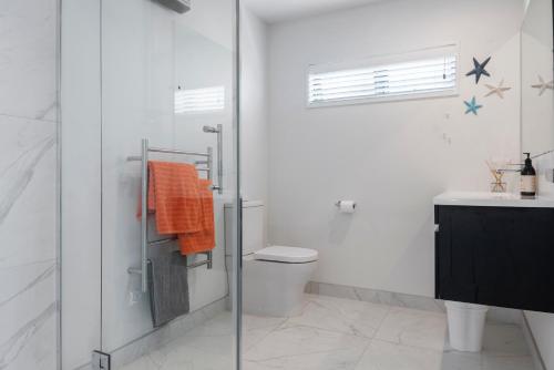 uma casa de banho com um chuveiro, um WC e um lavatório. em Soleil on Omana - Omana Beach Holiday Home em Maraetai
