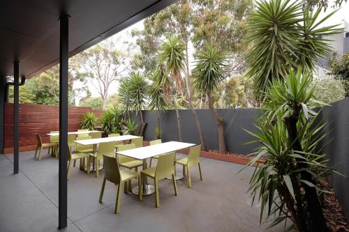 a patio with tables and chairs and palm trees at Together Co-Living Melbourne in Melbourne