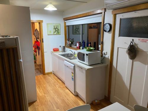 a small kitchen with a microwave and a sink at Summertime Cottage in Southport