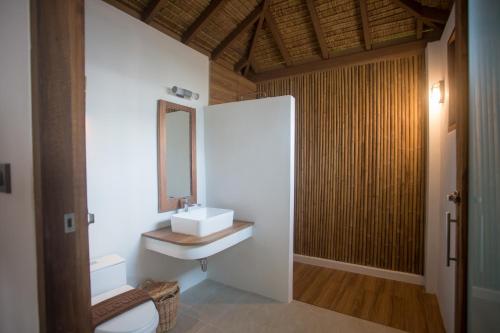 a bathroom with a sink and a toilet and a mirror at The Nest Private Beach Resort in Chumphon