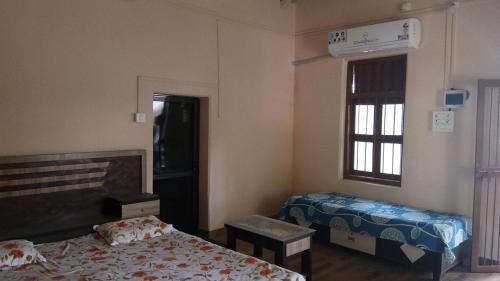 1 dormitorio con 2 camas y ventana en Kamat Cottages en Dāhānu