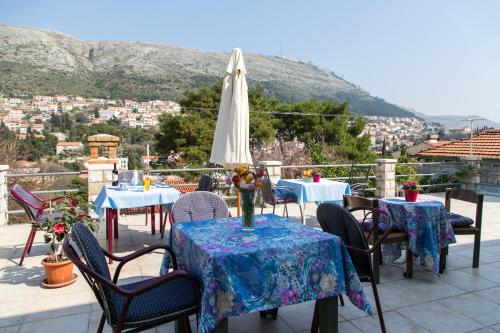 un patio con mesas, sillas y una sombrilla en Guest House Raguž, en Dubrovnik