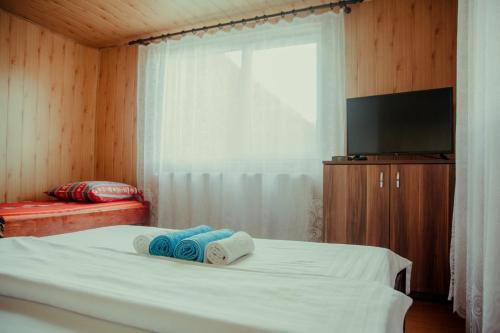a bedroom with a bed with towels and a flat screen tv at Cabana Săcuieu Vlădeasa in Săcuieu