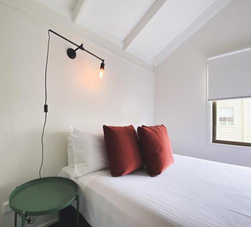 a bedroom with a bed with red pillows and a lamp at Nepean Shores by Gateway Lifestyle Holiday Parks in Penrith