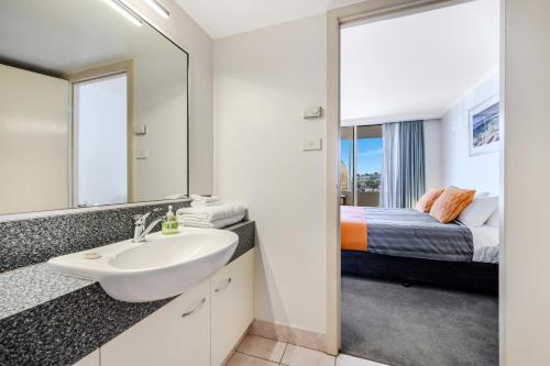 baño con lavabo y cama en Jenatt Apartments Salamanca, en Hobart