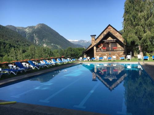 a pool at a resort with chairs and a building at Hotel Petit Lacreu in Salardú