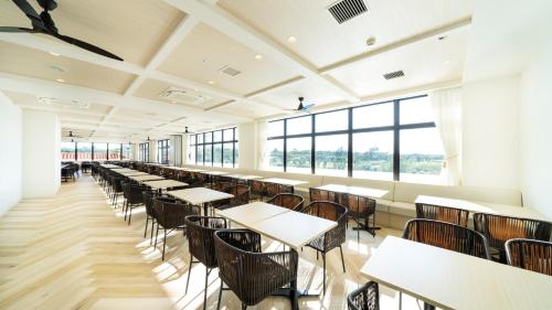 a cafeteria with tables and chairs and windows at Hotel Torifito Miyakojima Resort in Miyako-jima