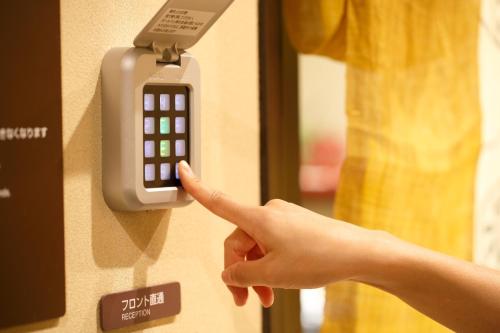 a person pointing to a remote control on a wall at Dormy Inn Premium Wakayama Natural Hot Spring in Wakayama