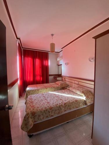 two beds in a room with red curtains at Lavinia Apart & Hotel in Alanya