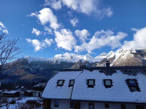 a house with snow covered mountains in the background at Guest house Vila Korošec in Bovec