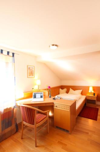 a bedroom with a bed and a desk with a computer at Landhotel Schöll in Parsberg