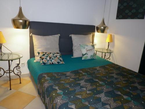 - une chambre avec un lit avec des oreillers et 2 tables dans l'établissement Arena Résidence, au Cap d'Agde