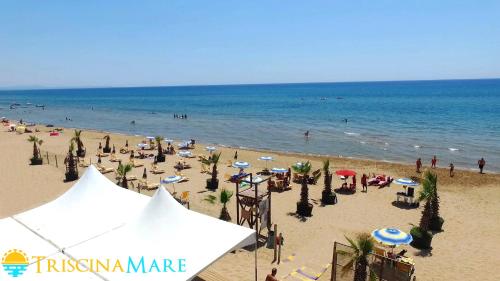 a beach with a crowd of people and the ocean at Triscinamare Hotel Residence in Triscina